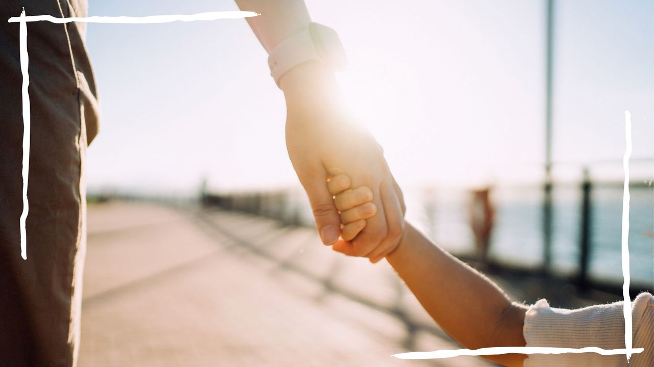 adult and child holding hands walking next to beach