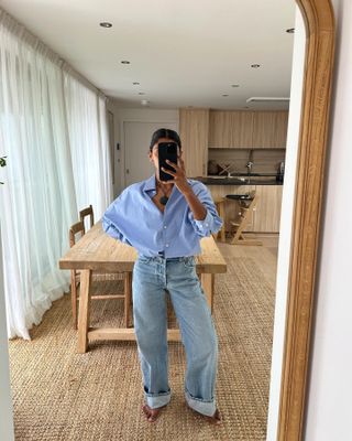 @monikh wears a blue Oxford shirt with blue jeans in her home