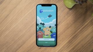 An iPhone on a desk with the Mastodon app open on its screen.