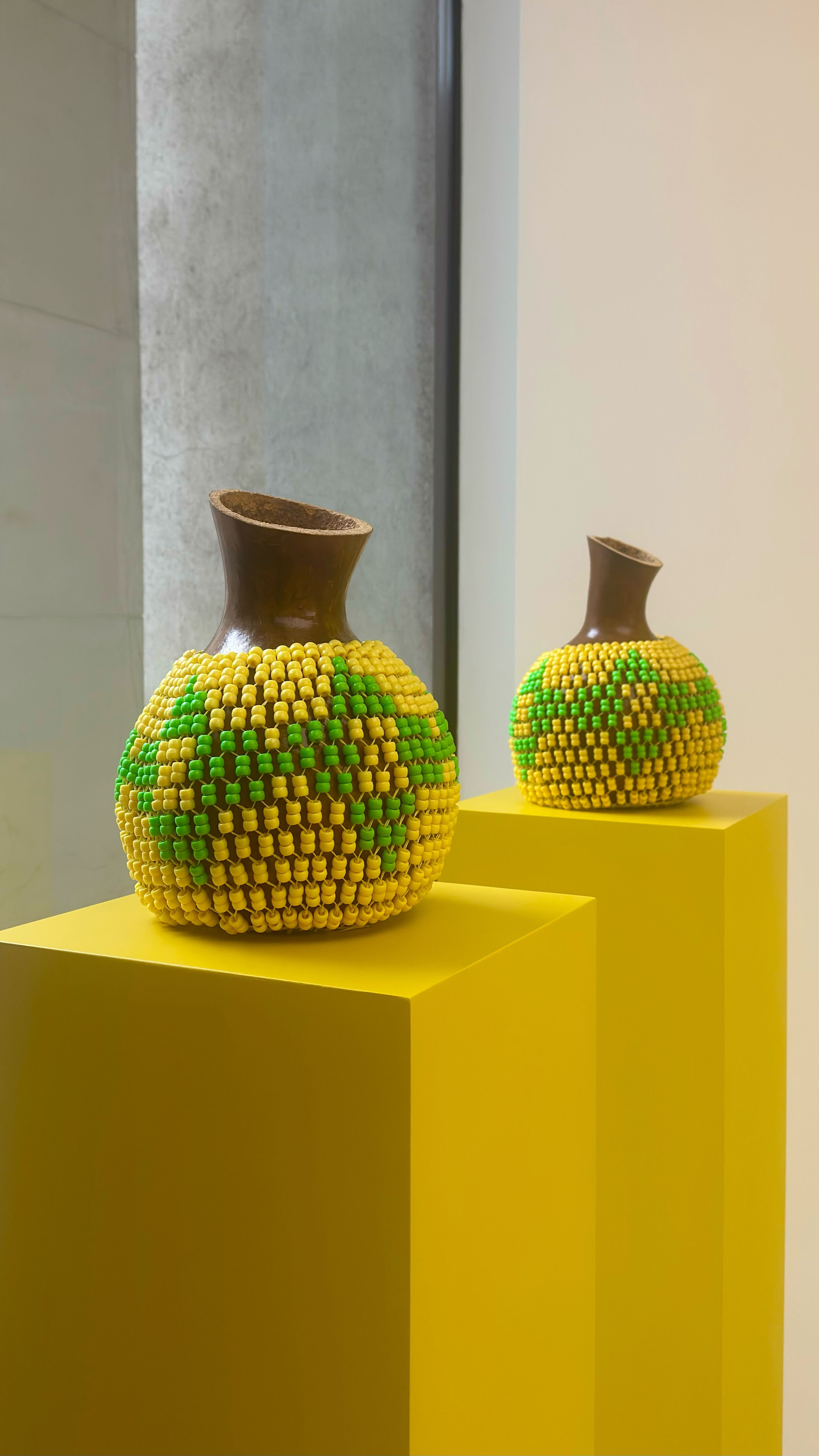 Two custom-made shekere decorated with green and yellow beads on yellow blocks