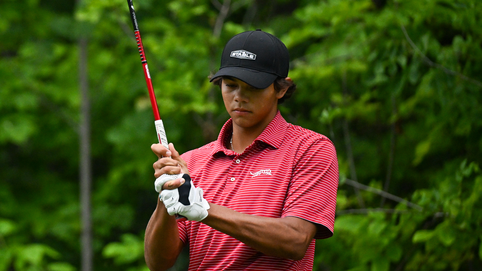 Charlie Woods checks his grip before a tee shot