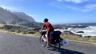 Isobel's partner with sufboard on bike