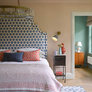 A bedroom with large double bed and glass ceiling light hung above with wall light to side of bed