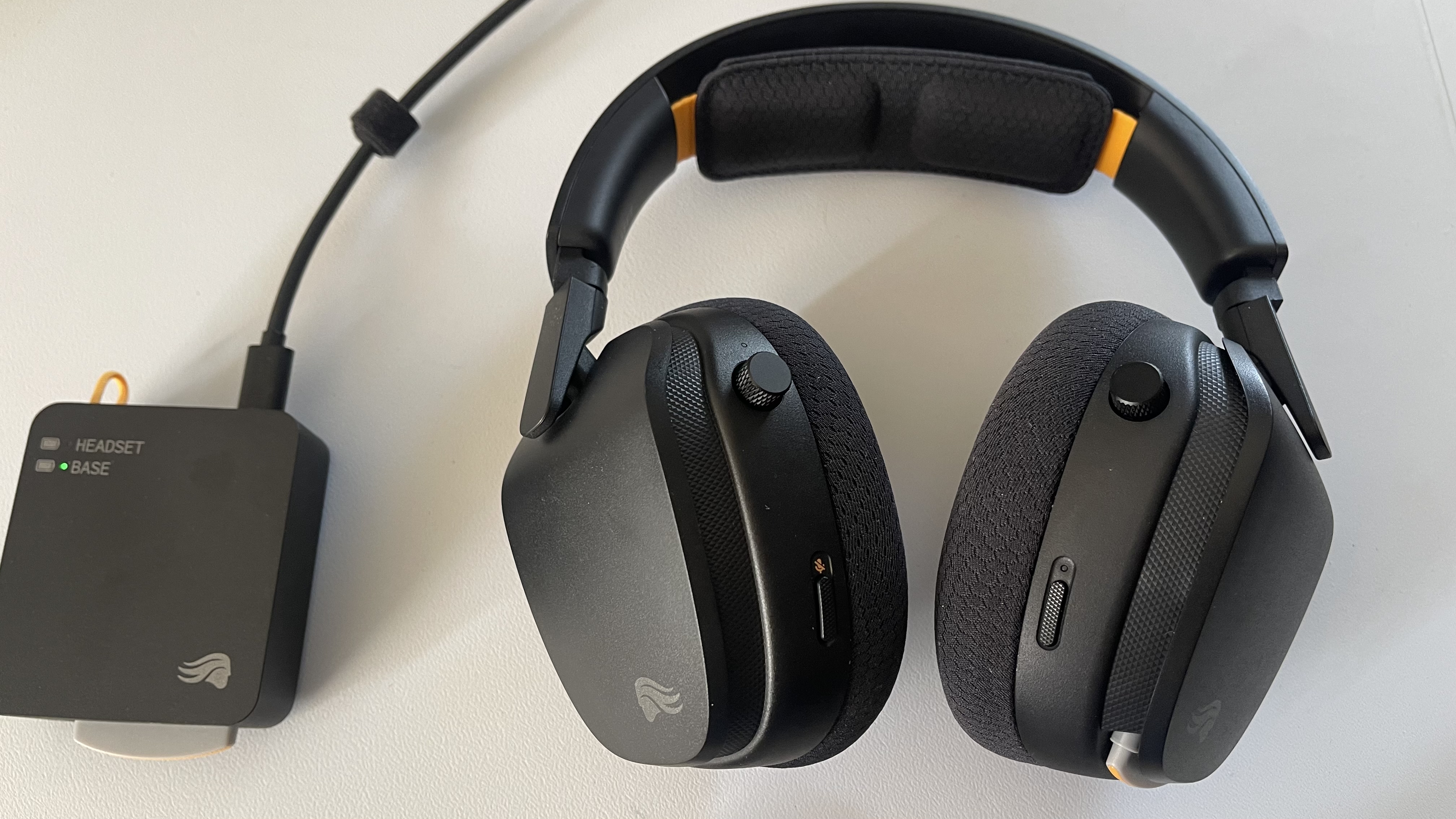 The Glorious GHS Wireless InfinitePlay gaming headset in black and orange on a plain white desktop.