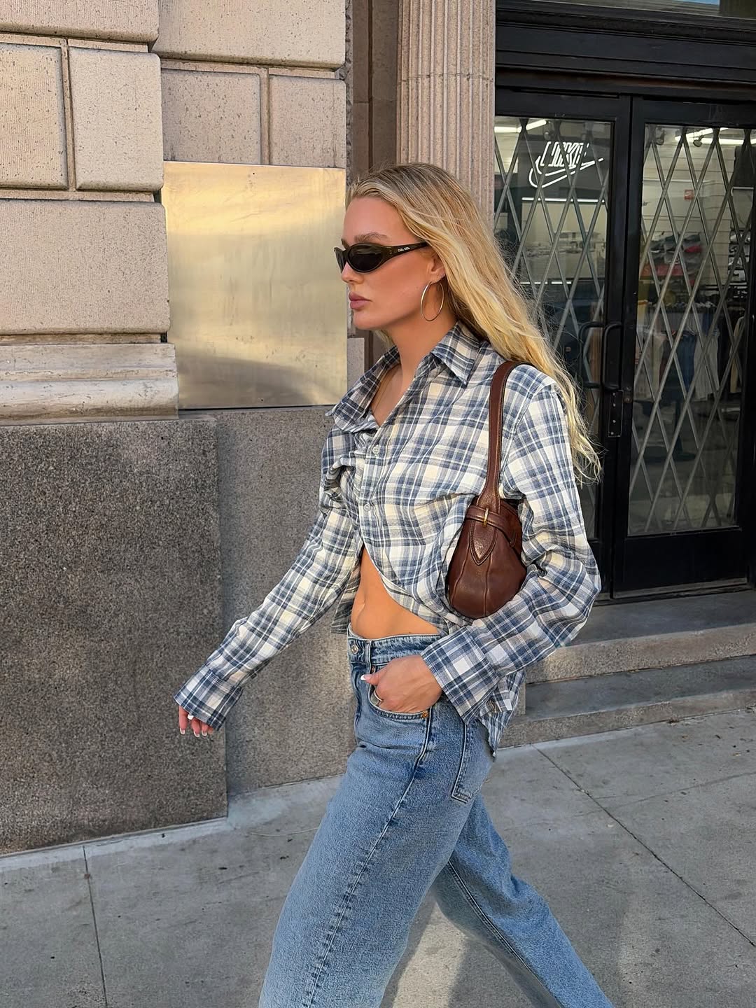 A woman wearing fitted button down shirt, one of the biggest 2026 spring to summer transitional trends.