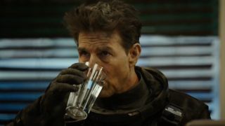 Tom Cruise as "Maverick" drinking water after surviving plane crash in Top Gun: Maverick