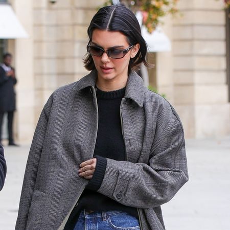 Kendall Jenner walks in Paris wearing a gray coat with straight leg jeans and ballet flats