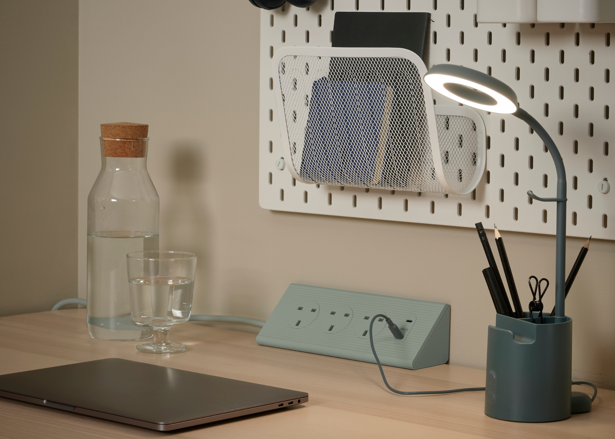 IKEA SKOTAT Extension cord in green on a desk with desk accessoried