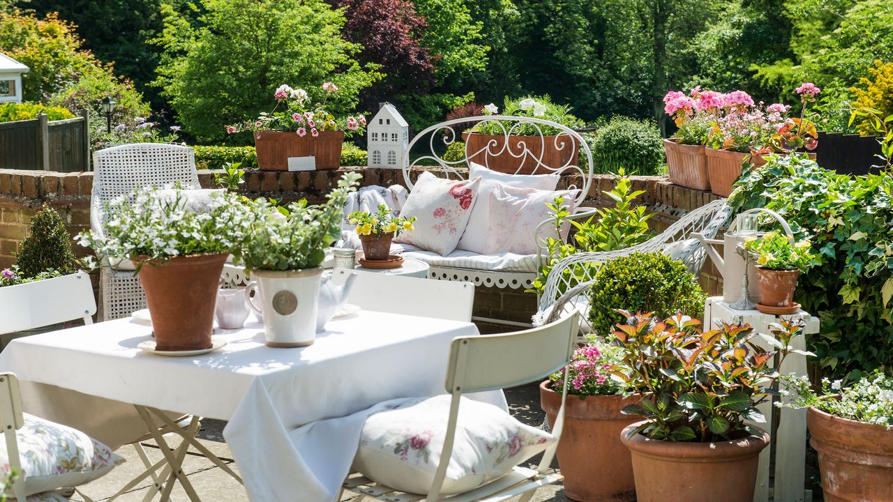 patio gardening ideas: containers on stone wall around patio seating