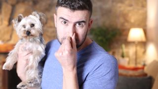 Man holding his nose while holding smelly dog