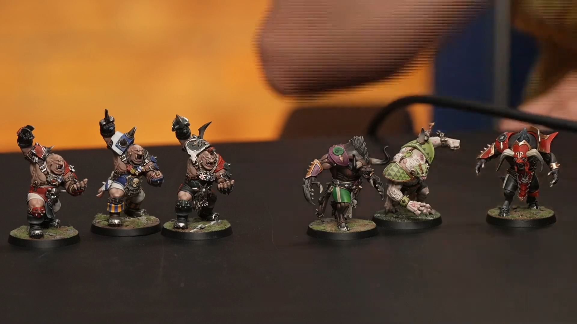 An array of larger Blood Bowl miniatures on a dark table