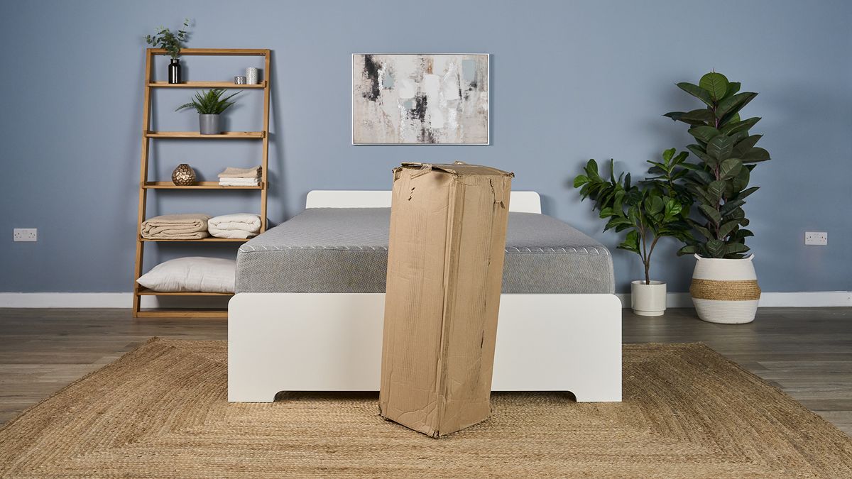 The Helix Dual Mattress Topper still in its shipping box, positioned in front of the Siena Signature Mattress.