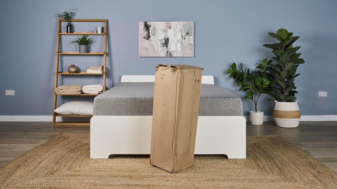 The Helix Dual Mattress Topper still in its shipping box, positioned in front of the Siena Signature Mattress.
