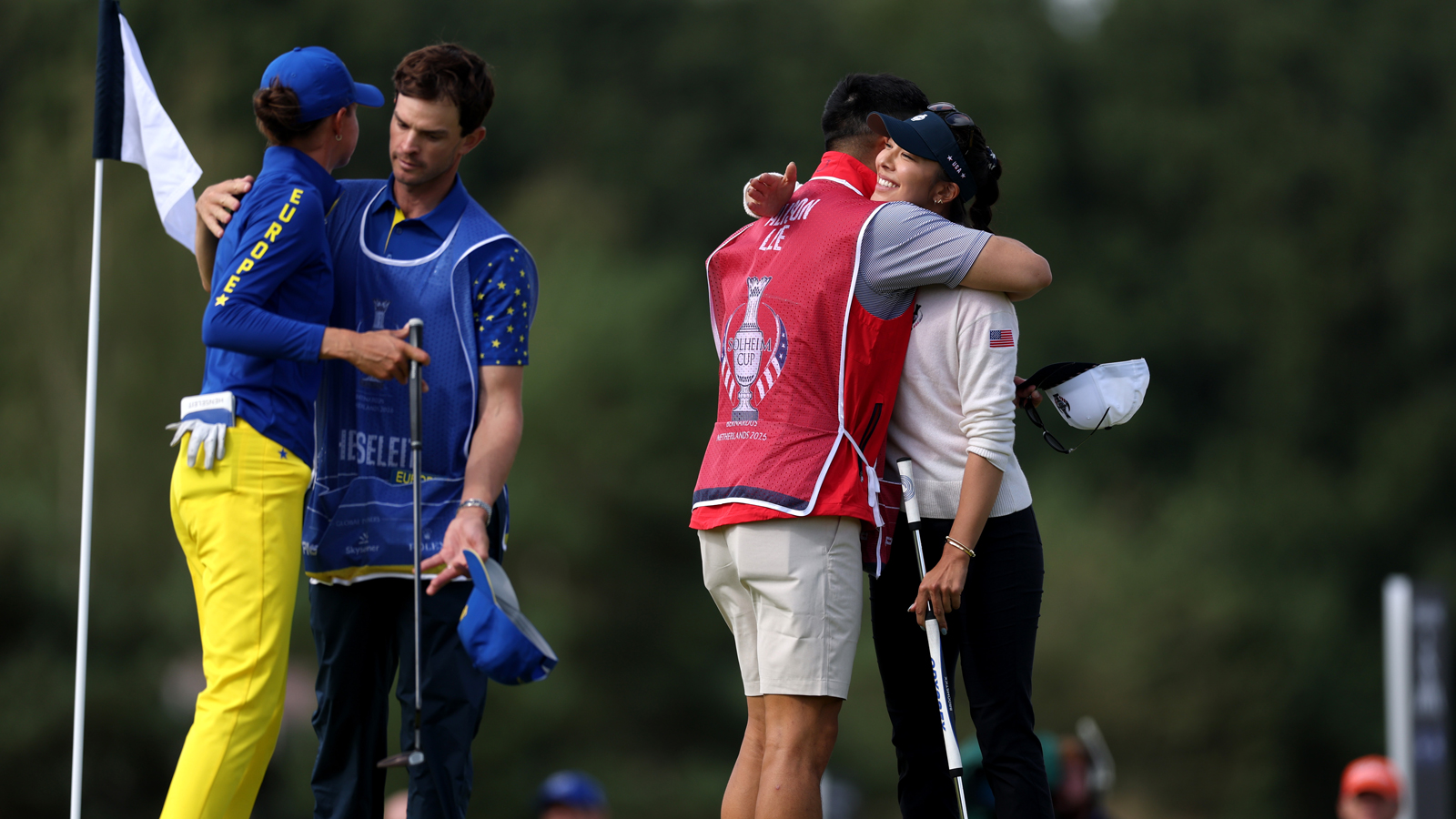 Two players hug their caddies at the Solheim Cup