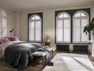 Made-to-measure curved window shutters in a bedroom