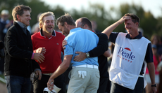 A group of golfers hug on the 18th