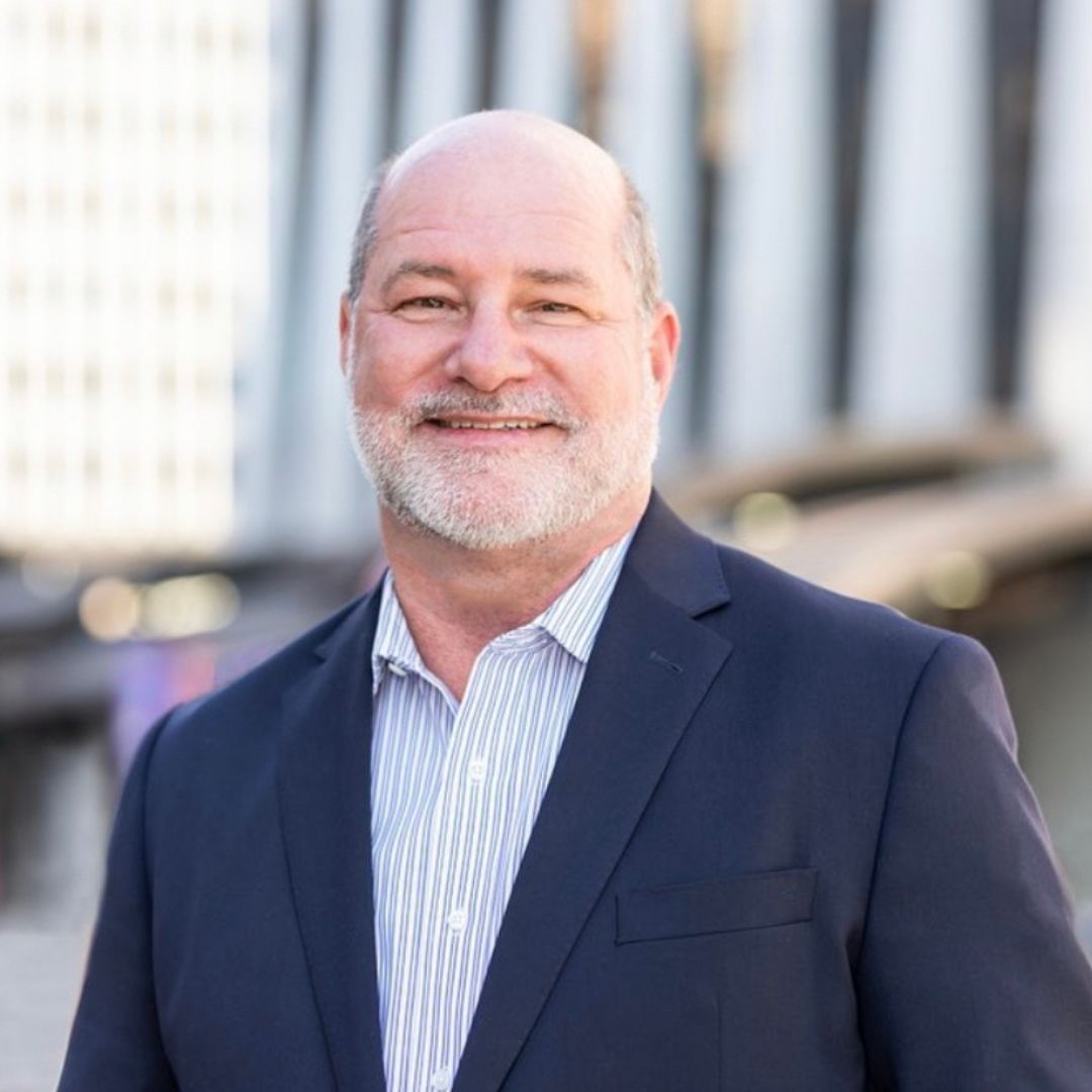 Headshot of brain researcher Dr. Patrick Porter wearing a navy blazer and pin strip blue and white shirt 
