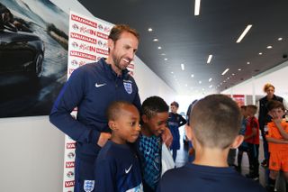 Gareth Southgate poses for a picture with two young fans inside a Vauxhall dealership