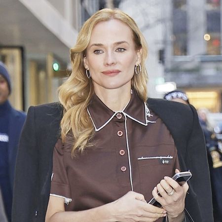 Diane Kruger wearing a brown Prada polo shirt, black coat, black leggings, and black leather knee boots in NYC