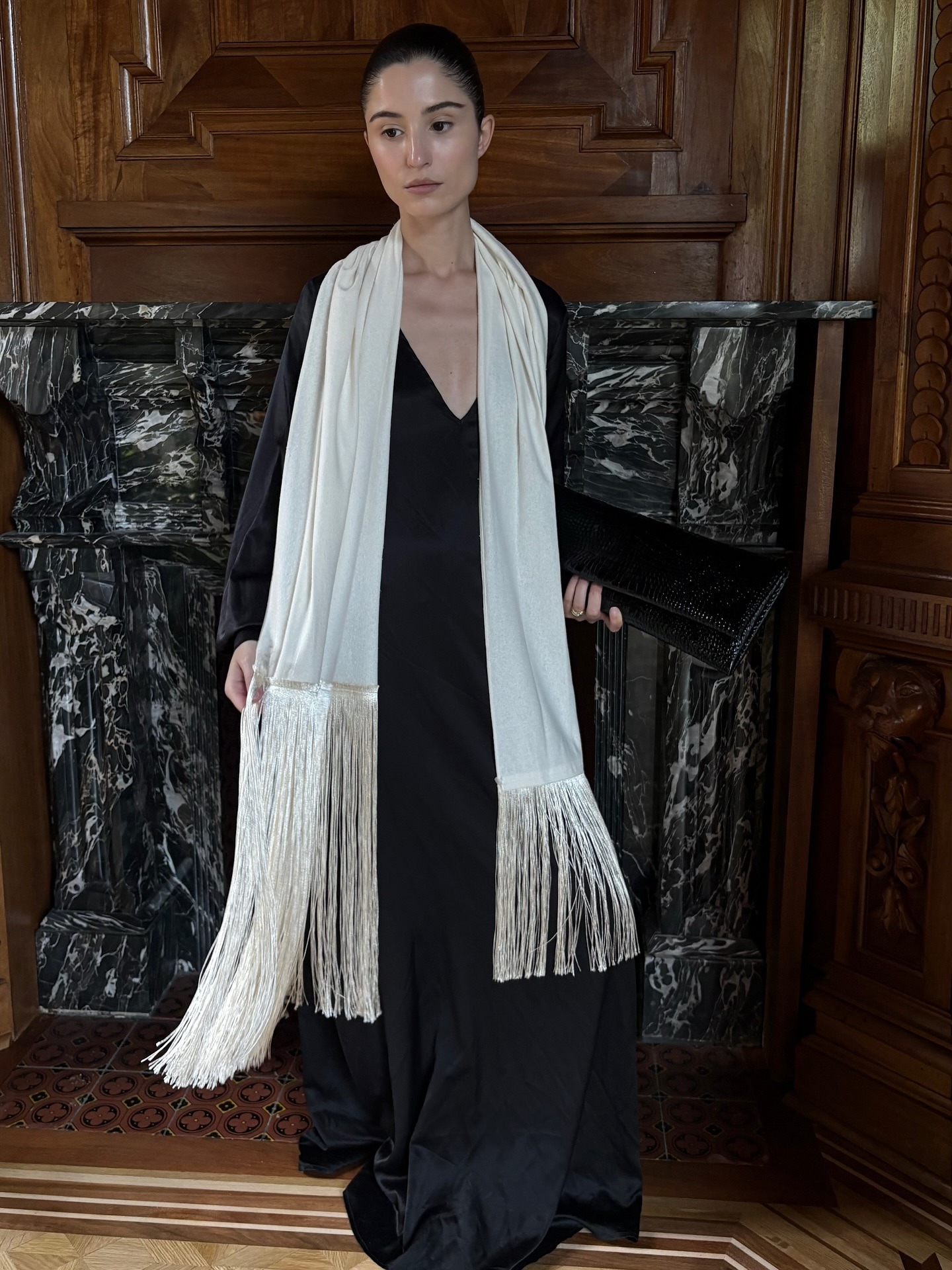 Influencer wearing black dress and white satin silk fringe scarf.