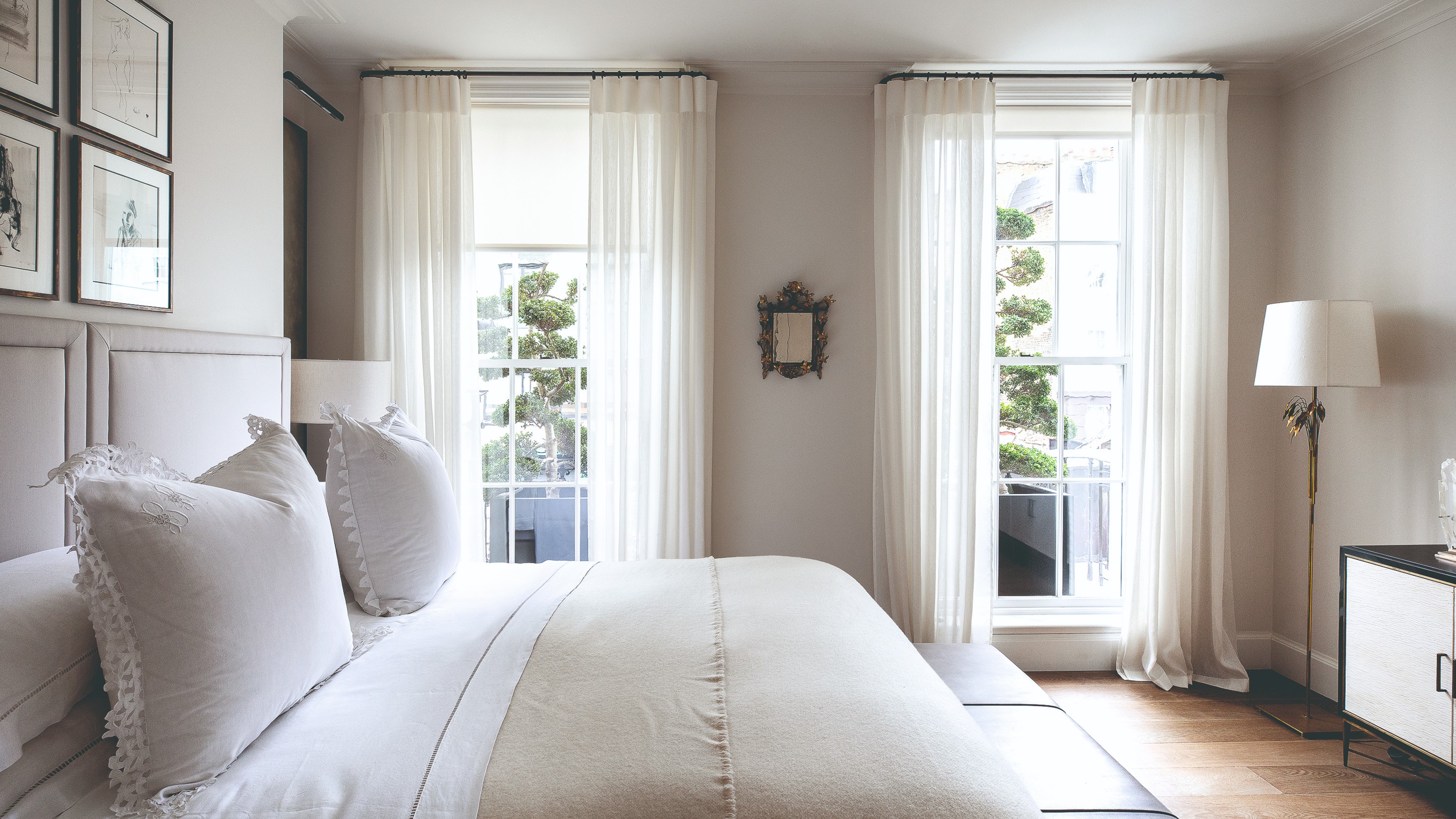 A white bedroom with white voile curtains on the windows