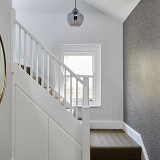 white hallway with grey wallpaper white window and staircase