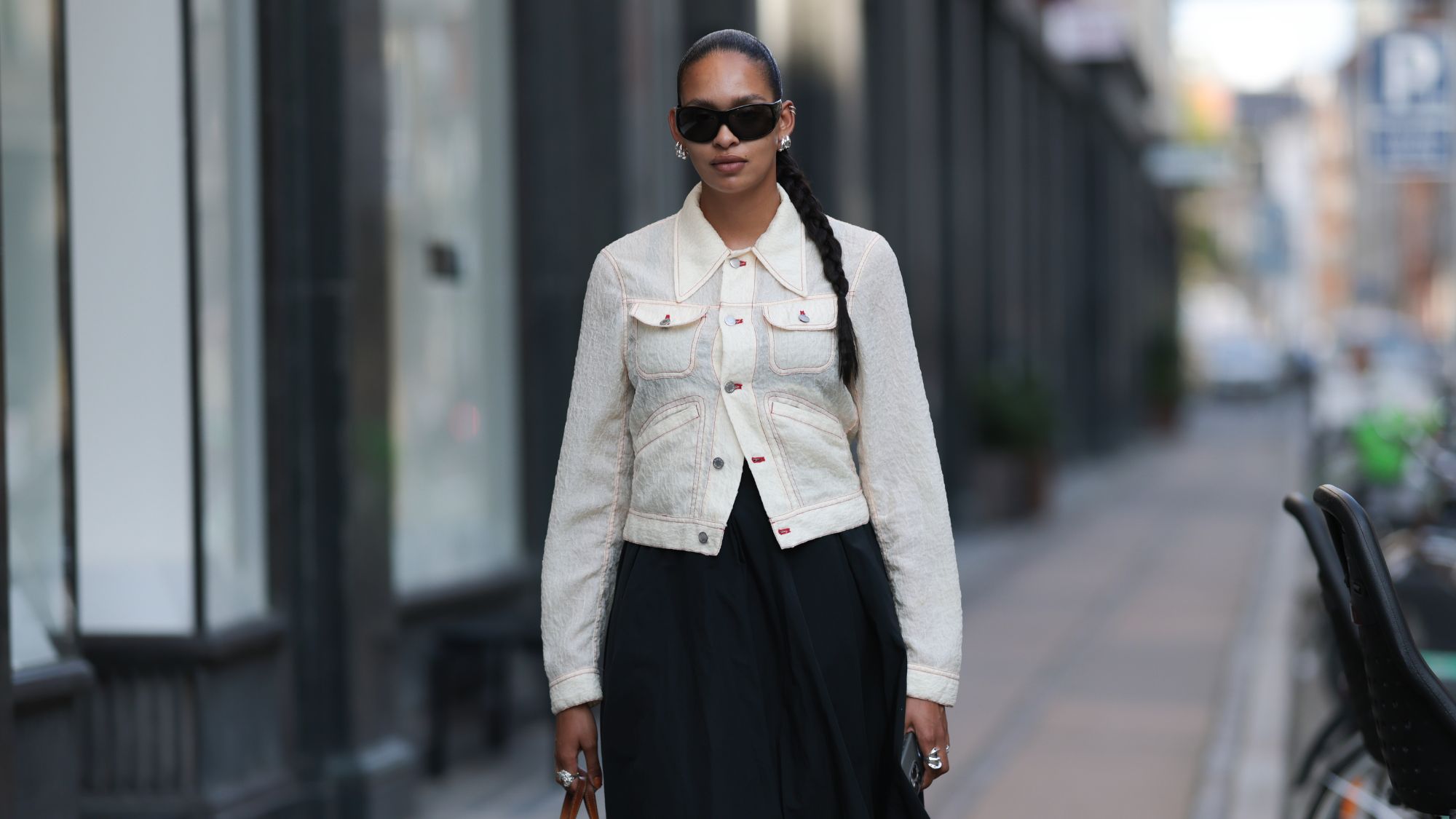 street style shot of woman wearing black sunglasses and white jacket