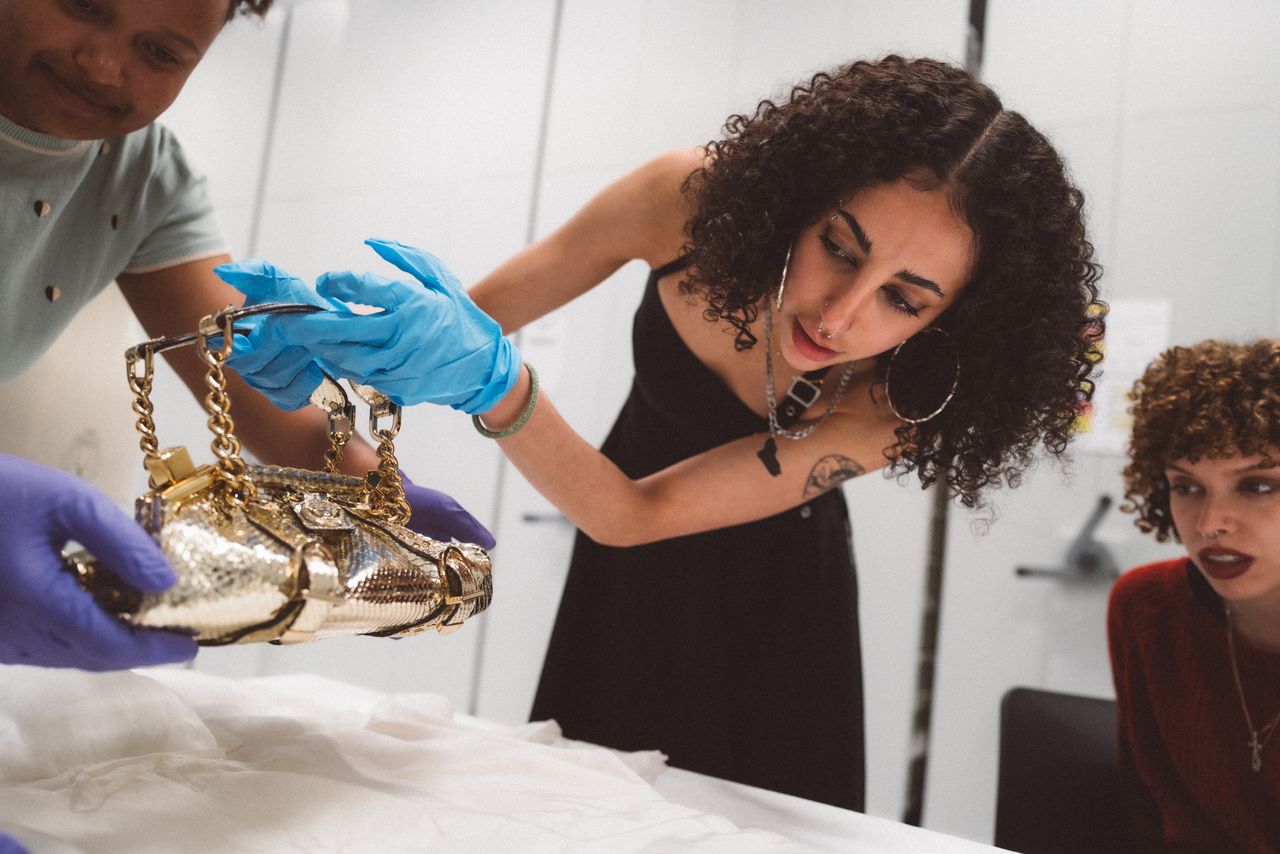 A group of young people observes a series of colorful, sculptural artifacts up close in a museum's specialized unit.