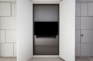 TV behind wardrobe style doors in bedroom