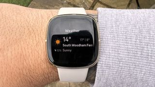 Fitbit Sense on wrist outside showing weather