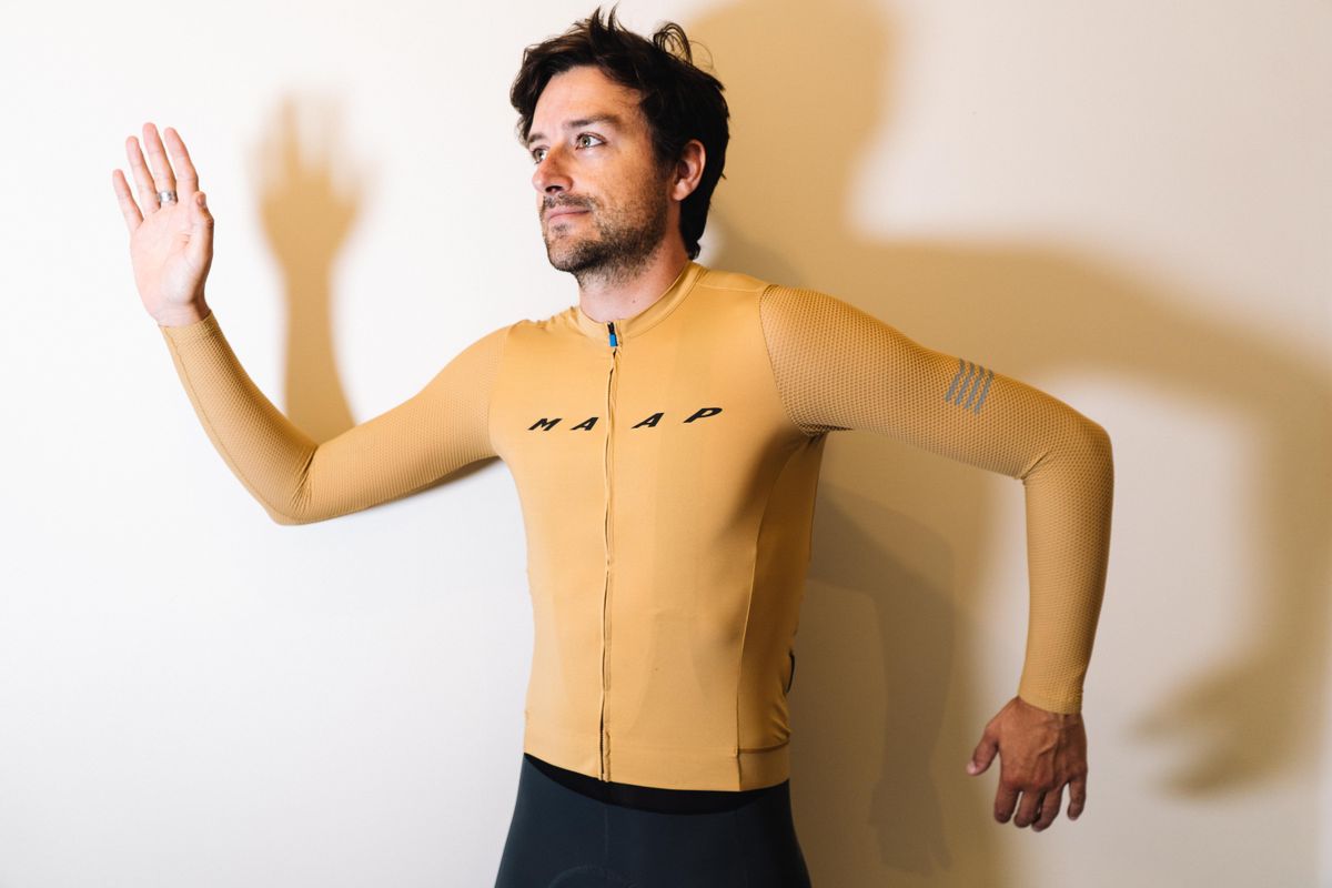 A white man in a tan jersey against a white wall