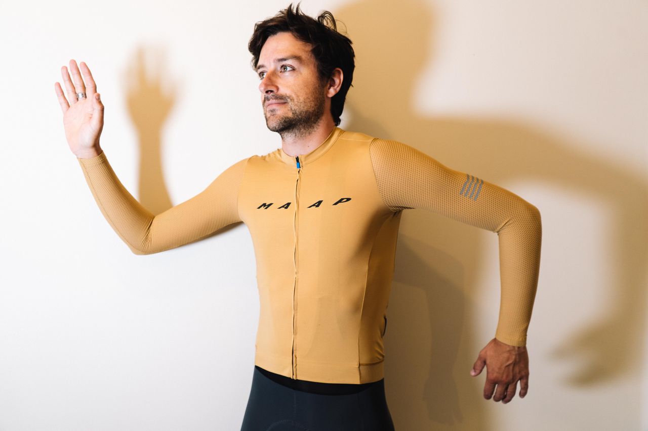 A white man in a tan jersey against a white wall
