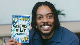 man with dark hair and a beard holding up a book that says Big Manny Science is Lit