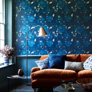 blue living room with printed wallpaper and bronze velvet sofa