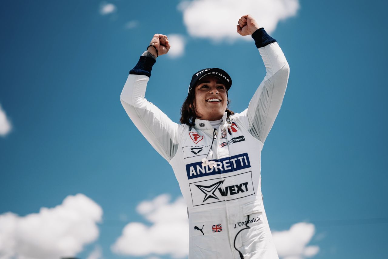 Woman in white racing overalls celebrating a win