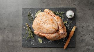 A raw turkey with spices on top for seasoning