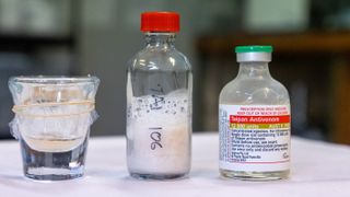 From left to right, we see a shot glass containing snake venom, a bottle of freeze-dried venom and a bottle of antivenom.