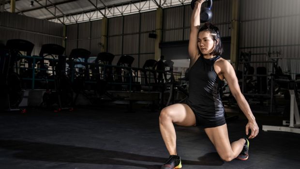 Woman performs lunge and press with kettlebell