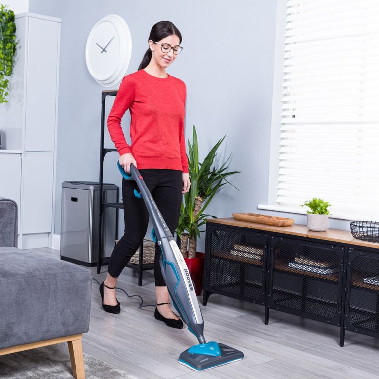 A woman in a red top cleaning a kitchen floor with a Hoover steam cleaner