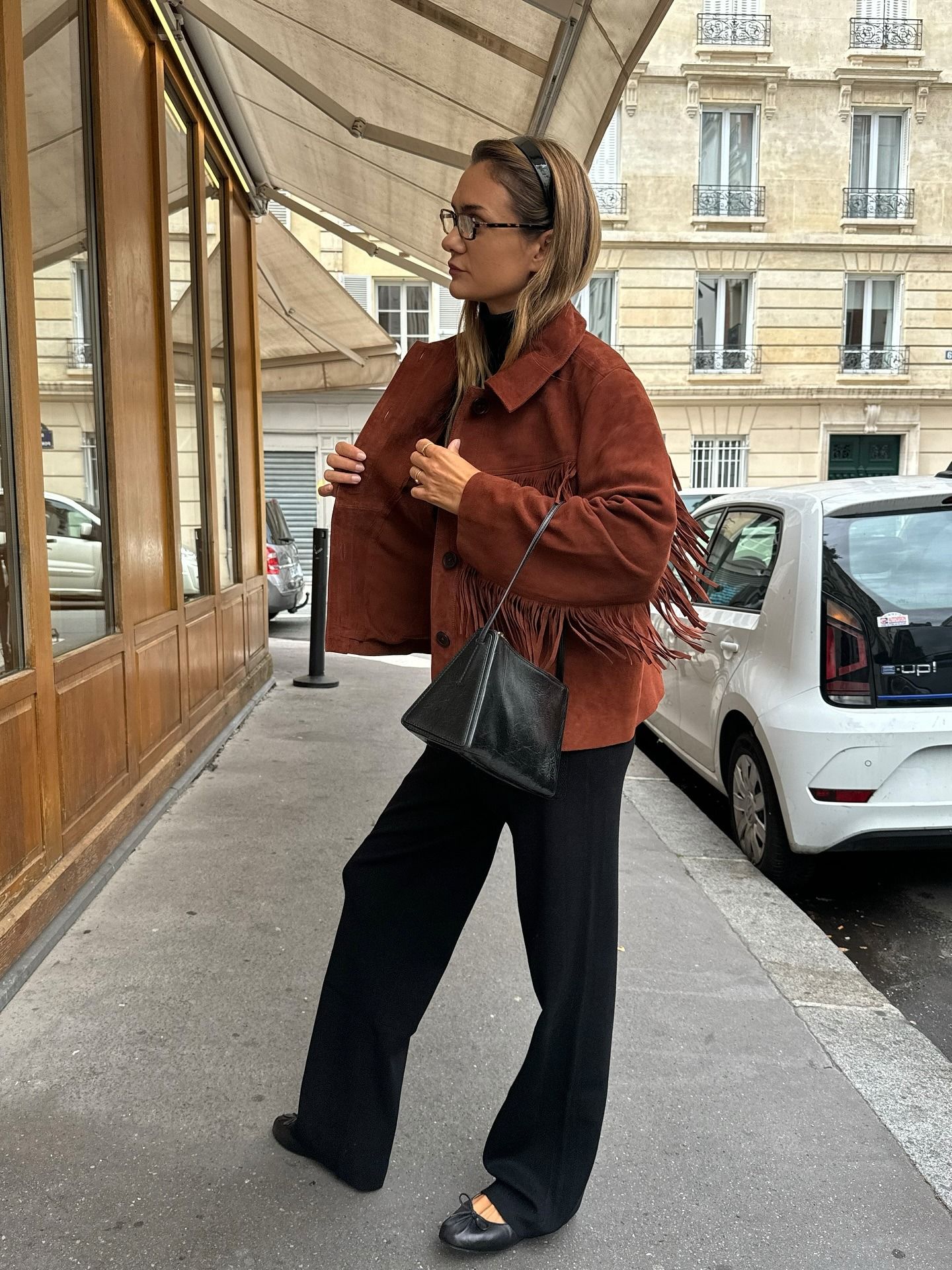 Anne wears a fringe jacket, black baggy pants, and black ballet flats.