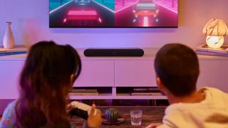 Sonos Ray under fjernsyn i en stue med lilla lys.
