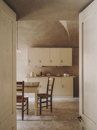 A kitchen with light pink walls and cabinets