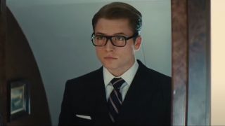 Taron Egerton looks at himself dressed sharply in a mirror in Kingsman: The Secret Service.