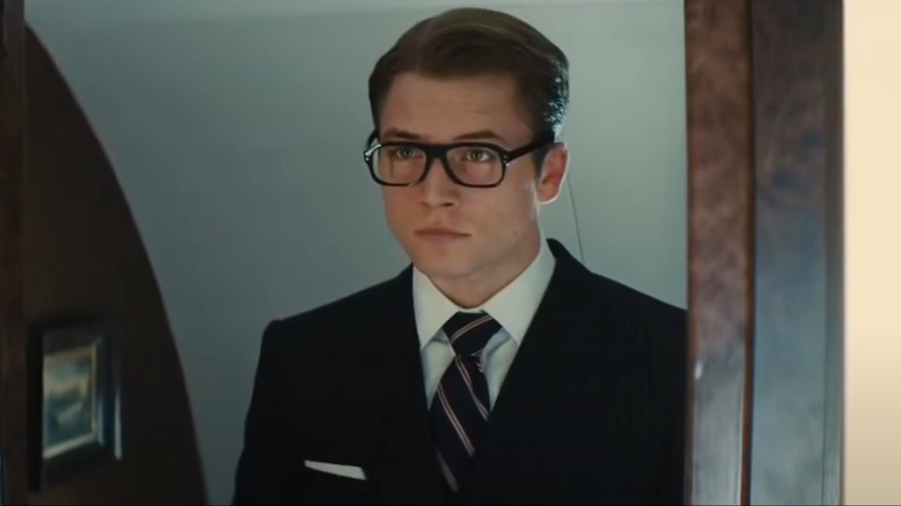 Taron Egerton se mira elegantemente vestido en un espejo en Kingsman: El Servicio Secreto.