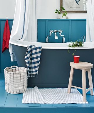 blue bathroom with freestanding tub and white bath mat