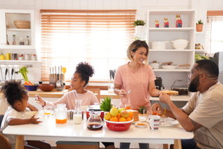 Family at the breakfast table eating Weetabix, fruit and juice