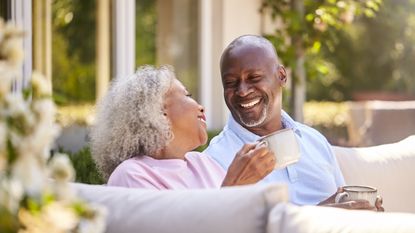 An older couple sits on the sofa and smiles about the outlook for seniors.