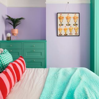 Lilac painted bedroom with green painted dresser and hanging sundae artwork