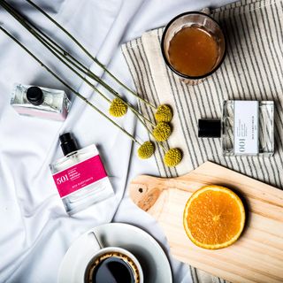 A selection of perfumes on table with other objects and coffee cup