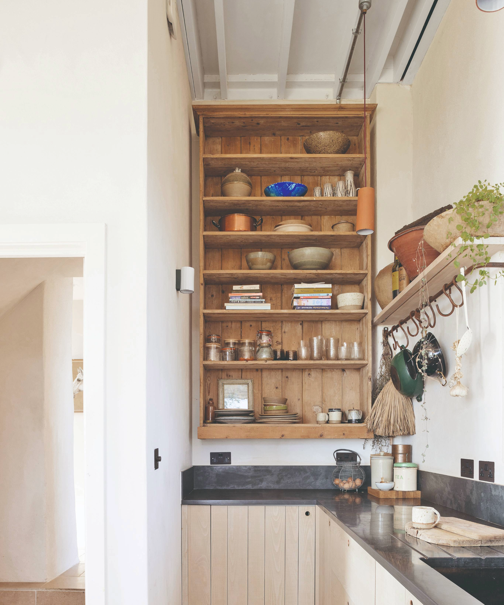Kitchen with open wooden shelf and pots hanging up on a rail